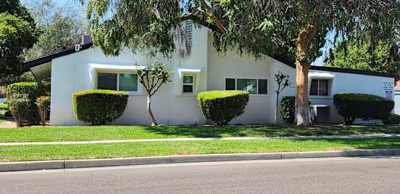 a white house with trees and bushes in front of it
