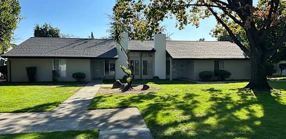 a white house with a yard and a tree