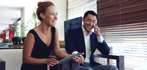 a man and woman sitting in a office talking on a cell phone