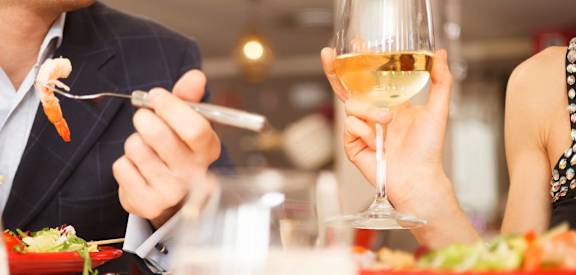 a man and woman sitting at a table with a glass of wine