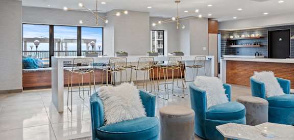 a lobby with blue chairs and a bar and a view of the ocean