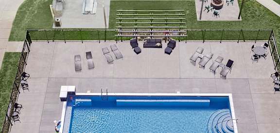 A pool with a blue tiled edge and a black fence surrounding it.