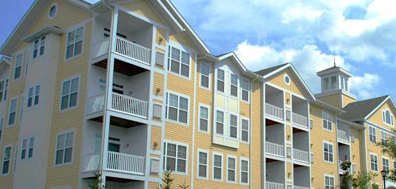 A large apartment building with balconies and a clock tower on the roof.