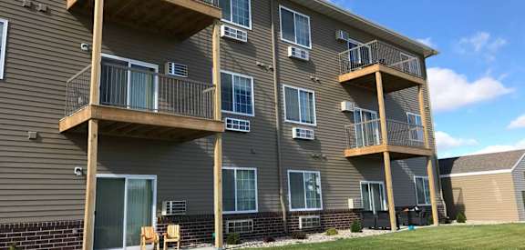 a building with three balconies and a grassy area in front of it at Courtyard Apartments, Moorhead, Minnesota