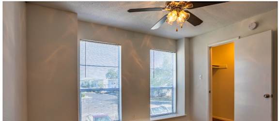 a bedroom with two large windows and a ceiling fan