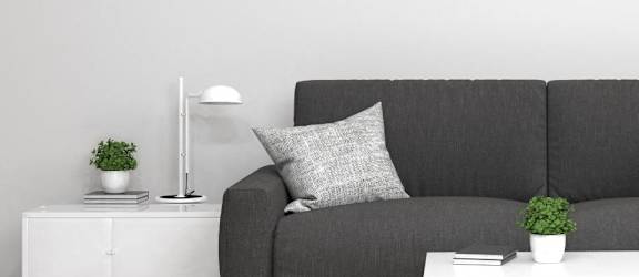 a couch in a living room with a white table and lamp