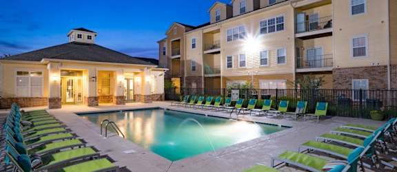 an apartment building with a swimming pool and chairs