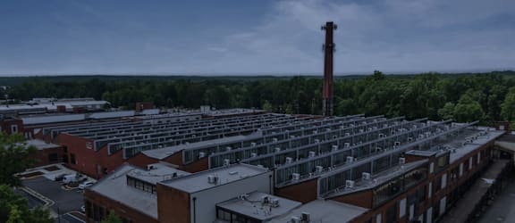 A large building complex with a tall chimney in the distance.