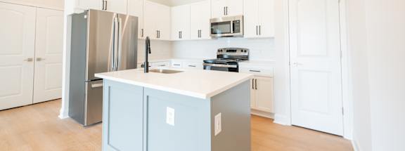 a large kitchen with white cabinets and stainless steel appliances