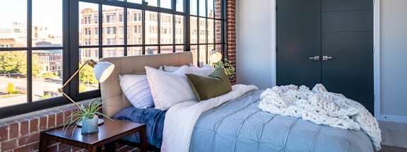a bedroom with a large window and a bed with a blue comforter