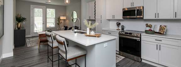 A modern kitchen with a large island and wooden floors. at The Cunningham Apartments, West Des Moines, Iowa