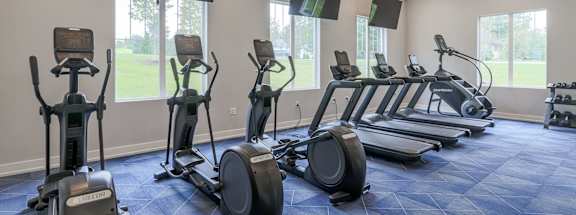 a gym with cardio machines and televisions