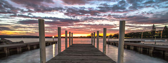 a dock on a lake with a sunset in the background