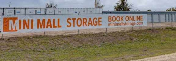 A sign for Mini Mall Storage with a website listed on it.