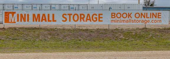 A billboard for Mini Mall Storage with the text "Book Online" and a website address.