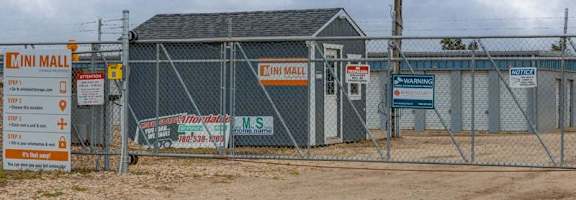 A construction site with a fence and a sign for a building materials store.