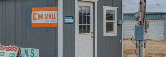 A small grey building with a white door and a sign that says "MINI MALL".