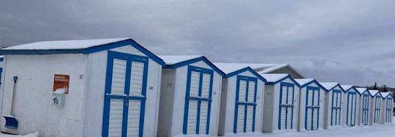 A row of blue and white buildings with snow on the ground.