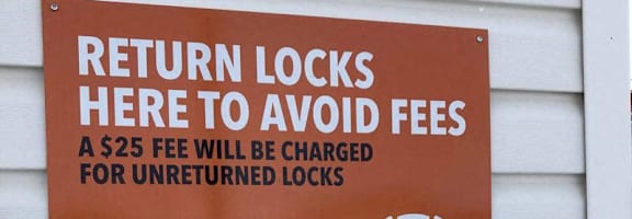 A sign on a wall instructs to return locks to avoid a $25 fee for unreturned locks.