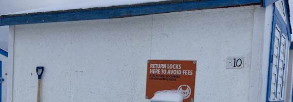 A sign on a building instructs to return locks to avoid fees.