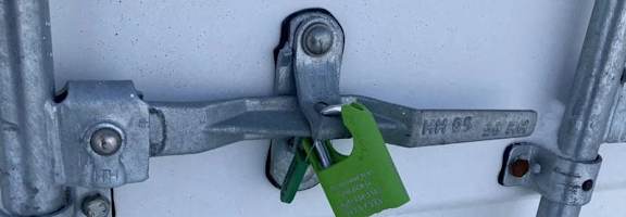 A green padlock is attached to a metal pipe.