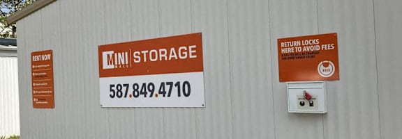A storage facility with a sign that reads "MINI STORAGE" and a phone number.