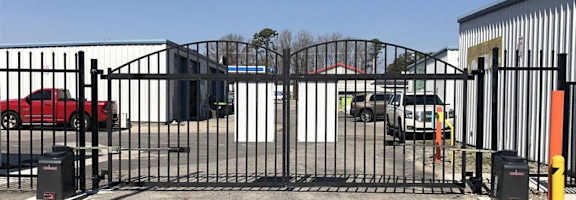A black metal gate blocks the entrance to a parking lot.