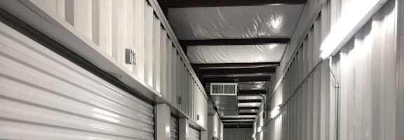 A long hallway in a storage unit with doors on both sides.