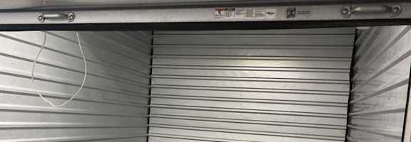 A storage unit with a closed grey shutter door.