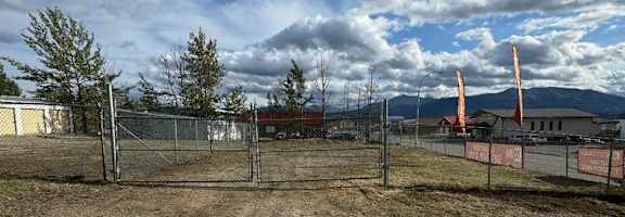 A construction site with a fence and a tree in the background.