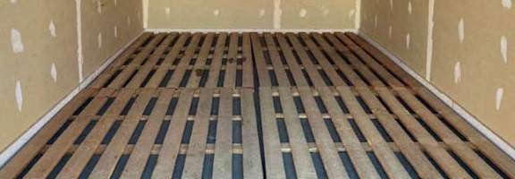A room with wooden flooring and walls covered in insulation material.