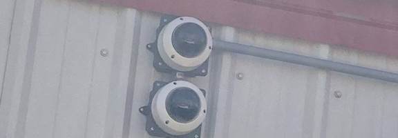 Two round cameras are mounted on a white wall.