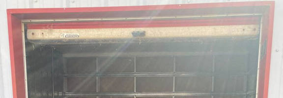 A red and white container with a metal grate door.