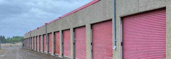 A long row of red garage doors on a concrete building.