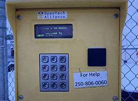 a yellow parking meter in front of a fence