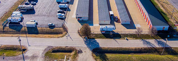 An aerial view of a parking lot with several cars and a large building with a red and white striped barrier.