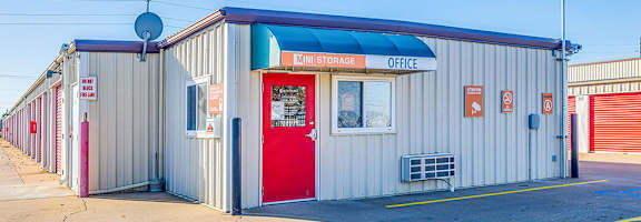 A storage office building with a red door and a blue awning.