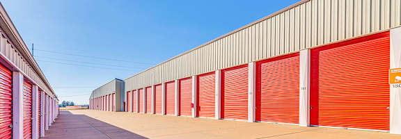 A long row of red storage units with a clear blue sky above.