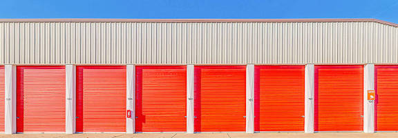 A storage facility with red doors and a grey roof.