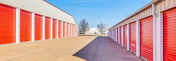 A long row of red and white storage units with a clear blue sky above.