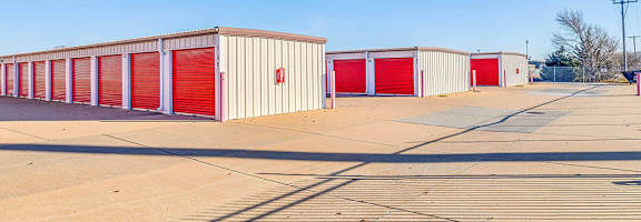 A row of red storage units are lined up in a parking lot.