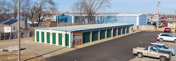 A large blue and green building with a parking lot in front.