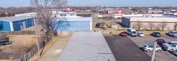 A large green and white storage unit is in the foreground of a parking lot.