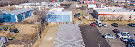A green and white striped building sits in the middle of a parking lot.