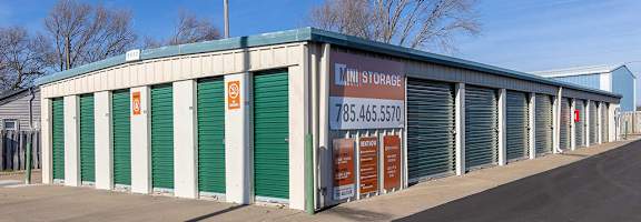 A storage facility with green doors and a sign that reads "Mini Storage".