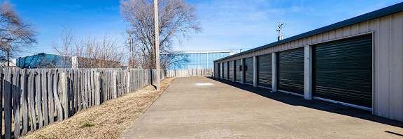 A long, empty driveway leads to a row of garage doors.