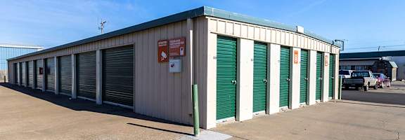 A storage facility with green doors and a red sign on the side.