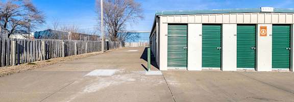 A parking lot with a building and green doors.