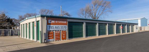 A storage facility with a sign that reads "MINI STORAGE" and a phone number.