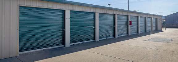 A long row of storage units with closed green doors.